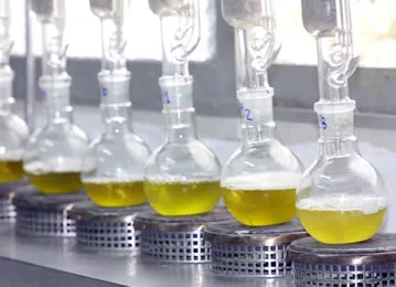 Glass beakers filled with yellow liquid, representing CBD oil extraction methods.