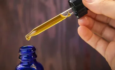 Hands holding a bottle of CBD oil and its dropper lid